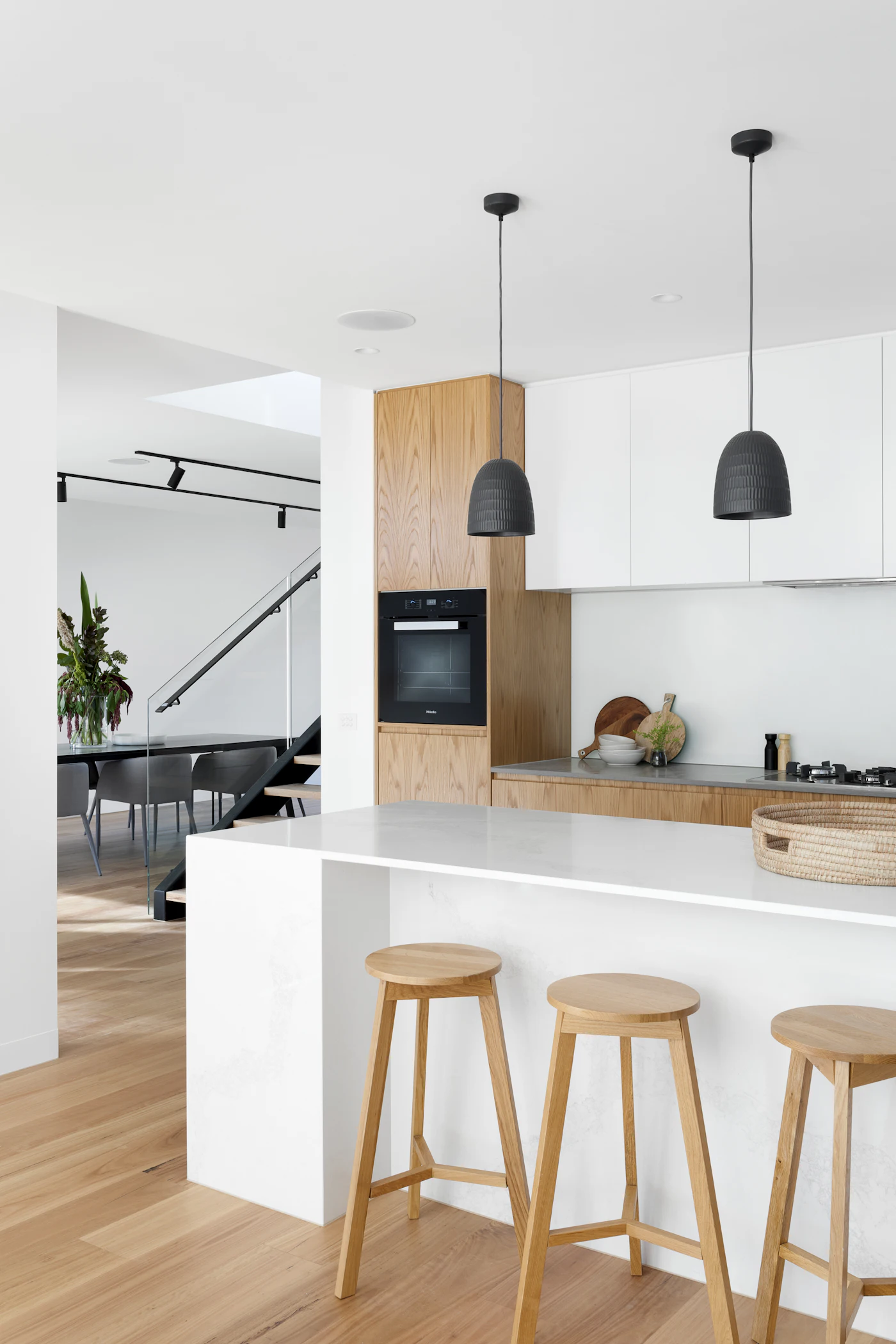Cuisine en chêne clair et blanc sur parquet bois, suspensions noires