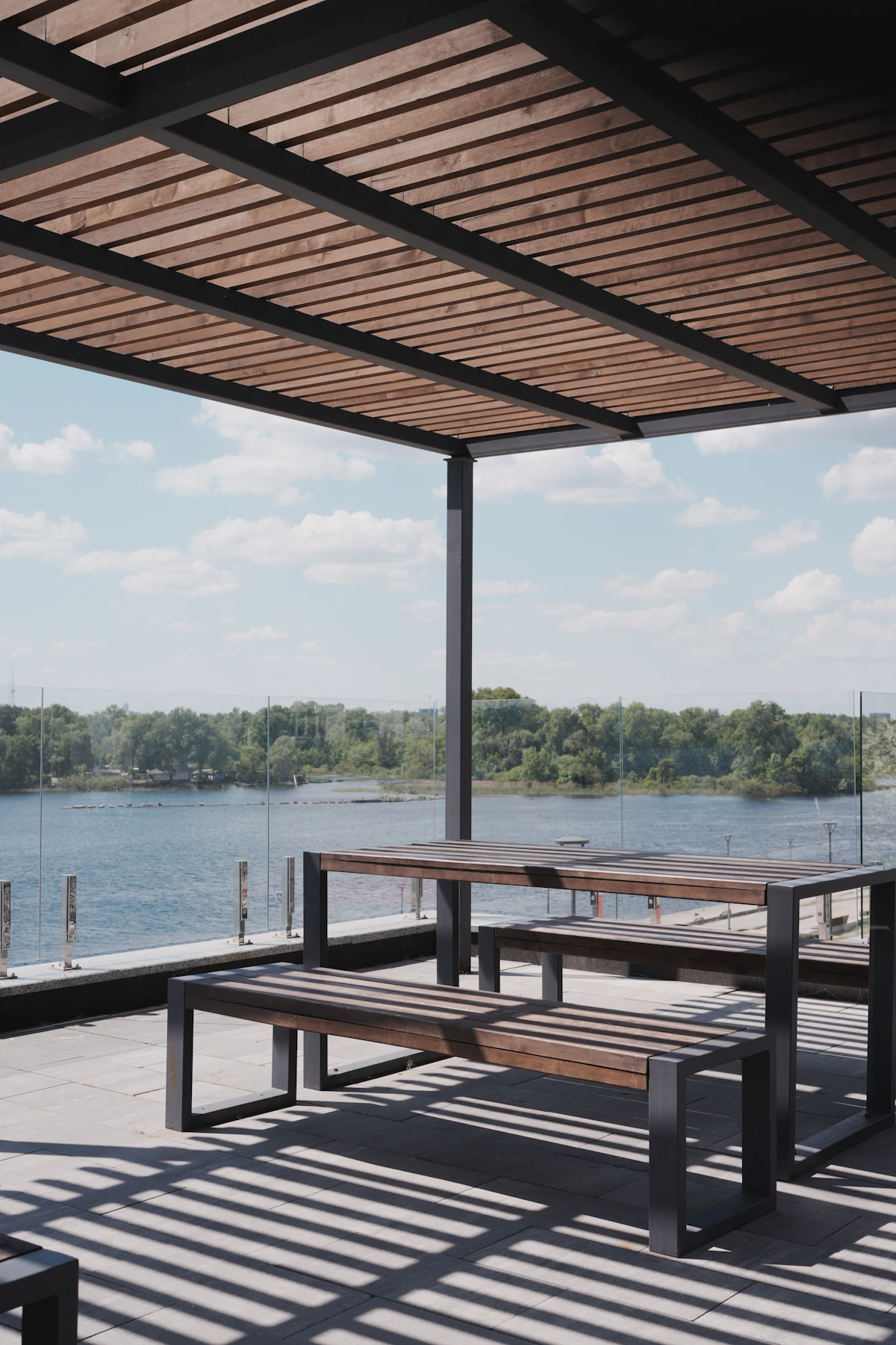 Pergola en lames de bois et structure noire au-dessus d'une terrasse